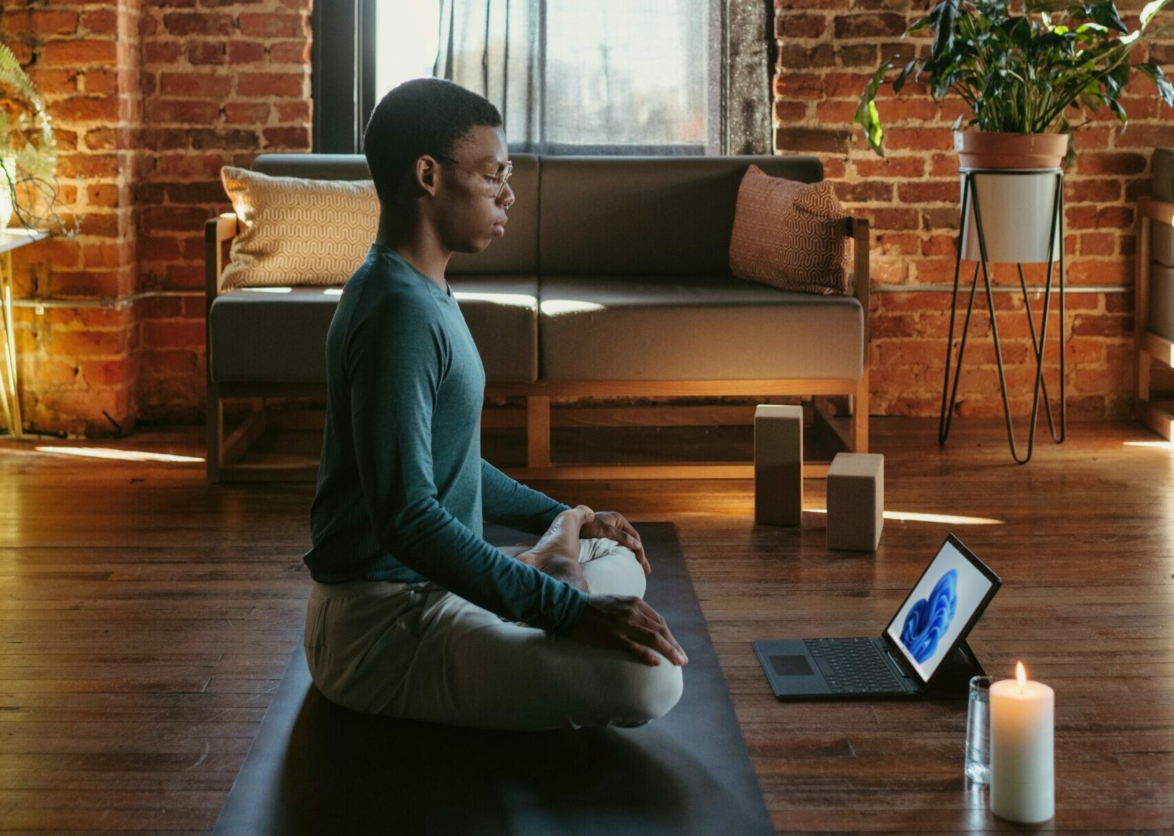 A young man seated on the floor doing an online meditation